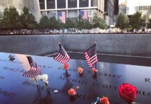 A poignant tribute at the 9/11 Memorial in NYC with flags and flowers honoring victims.