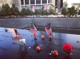 A poignant tribute at the 9/11 Memorial in NYC with flags and flowers honoring victims.