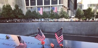 A poignant tribute at the 9/11 Memorial in NYC with flags and flowers honoring victims.