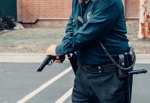 Житель Калгари обвинён в угрозах расстрелом в продуктовом магазине A police officer adjusting a firearm outdoors in a tactical situation, ensuring safety.