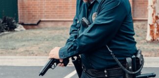 A police officer adjusting a firearm outdoors in a tactical situation, ensuring safety.
