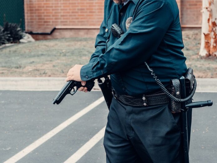 A police officer adjusting a firearm outdoors in a tactical situation, ensuring safety.