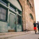 В Уитби арестован 19-летний парень за угрозы устроить стрельбу в синагоге A police officer escorts a handcuffed individual past a brick building.