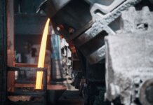 A powerful image of molten metal pouring in a heavy industry steel mill setting.