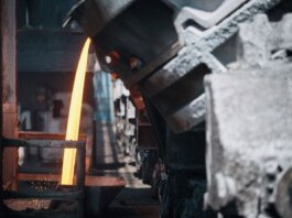 A powerful image of molten metal pouring in a heavy industry steel mill setting.
