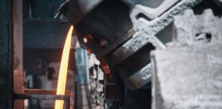 A powerful image of molten metal pouring in a heavy industry steel mill setting.