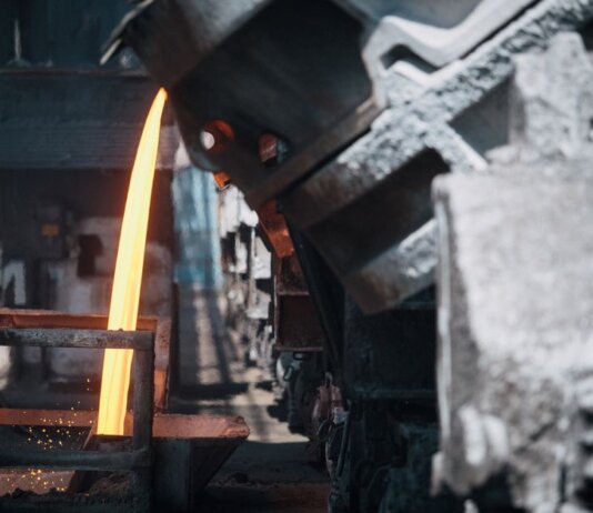 A powerful image of molten metal pouring in a heavy industry steel mill setting.