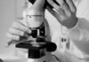 Shared Health продолжает работу лабораторий в расширенном режиме A scientist in a lab coat using a microscope for research in a laboratory setting.