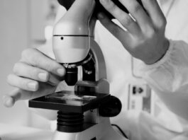 A scientist in a lab coat using a microscope for research in a laboratory setting.
