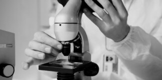 A scientist in a lab coat using a microscope for research in a laboratory setting.