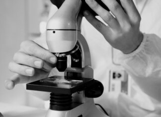 Shared Health продолжает работу лабораторий в расширенном режиме A scientist in a lab coat using a microscope for research in a laboratory setting.