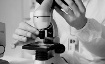 Shared Health продолжает работу лабораторий в расширенном режиме A scientist in a lab coat using a microscope for research in a laboratory setting.