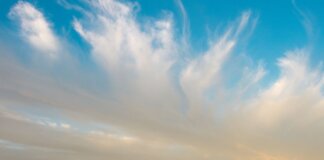 A vast prairie landscape in Saskatchewan with a rural road and dramatic clouds at sunset.