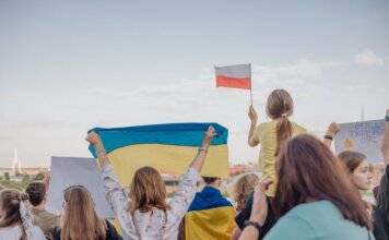 A vibrant demonstration in Szczecin, Poland featuring crowds waving Polish and Ukrainian flags in unity.