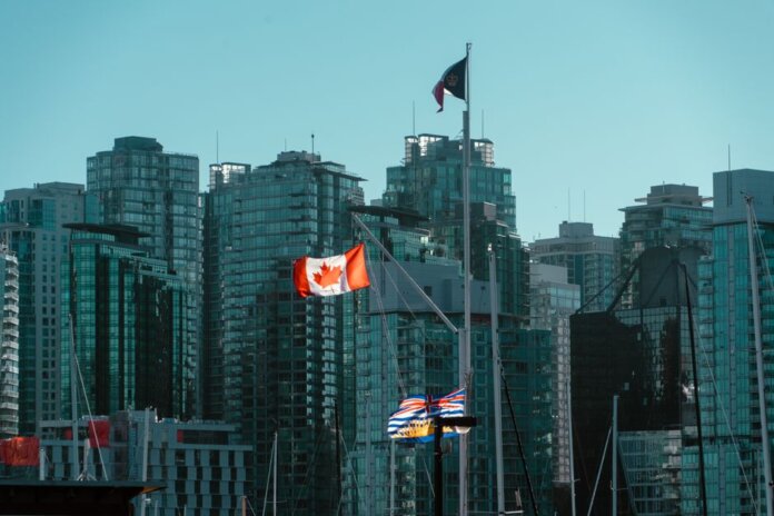 A view of Vancouver's glassy skyscrapers with Canadian and British Columbia flags waving in the foreground. A view of Vancouver's glassy skyscrapers with Canadian and British Columbia flags waving in the foreground.