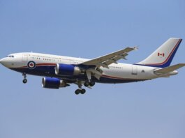 Airplane flying in clear blue sky with Canadian government livery.