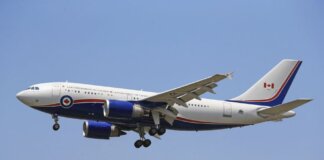 Airplane flying in clear blue sky with Canadian government livery.