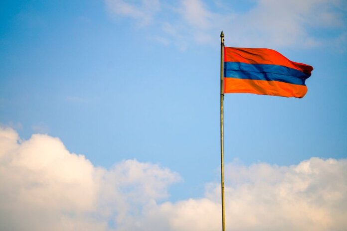 Armenian flag on a flagpole swaying in the windy blue sky with clouds. Armenian flag on a flagpole swaying in the windy blue sky with clouds.