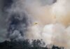 Aviation plane fights a massive forest fire, engulfed in thick smoke, showcasing emergency response.