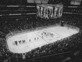 Black and white overhead shot of a thrilling ice hockey game with a full audience in an indoor arena.