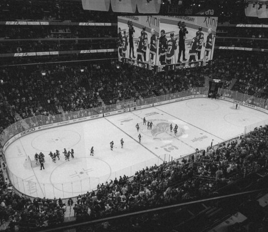 Black and white overhead shot of a thrilling ice hockey game with a full audience in an indoor arena.