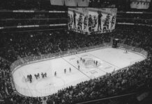Black and white overhead shot of a thrilling ice hockey game with a full audience in an indoor arena.