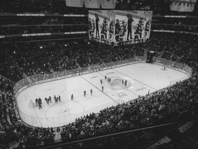 Black and white overhead shot of a thrilling ice hockey game with a full audience in an indoor arena.