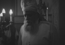 Black and white photo of an Orthodox priest during a candlelit religious ceremony in Cairo, Egypt.
