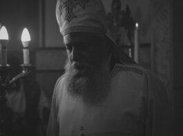 Black and white photo of an Orthodox priest during a candlelit religious ceremony in Cairo, Egypt.