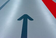 Blue arrow and red line on a parking garage floor signify direction and order.