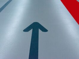Blue arrow and red line on a parking garage floor signify direction and order.