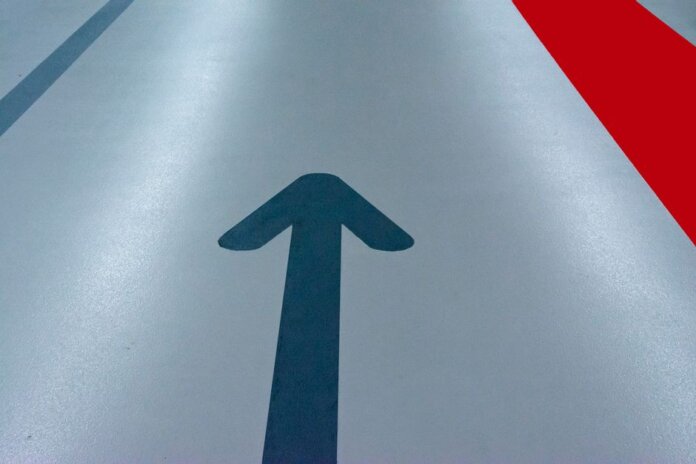 Blue arrow and red line on a parking garage floor signify direction and order. Blue arrow and red line on a parking garage floor signify direction and order.
