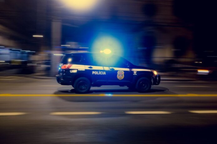 Blurred motion capture of a police car speeding at night with flashing lights on a city street. Blurred motion capture of a police car speeding at night with flashing lights on a city street.