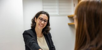 Businesswomen shaking hands in an office, representing a successful job interview or partnership.