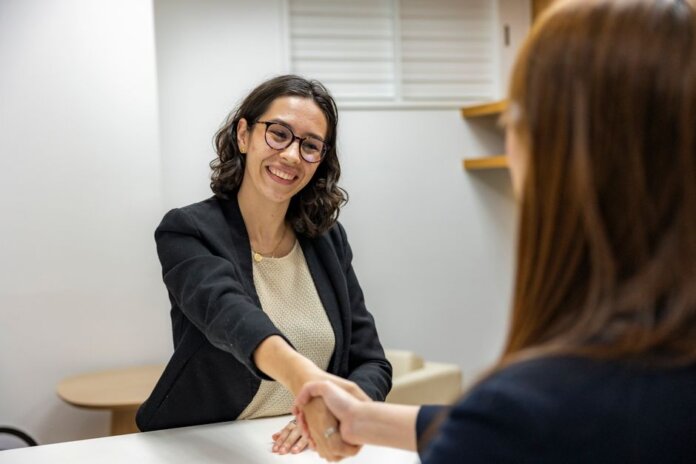 Businesswomen shaking hands in an office, representing a successful job interview or partnership. Businesswomen shaking hands in an office, representing a successful job interview or partnership.