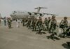Canadian military paratroopers walk past a C-17 Globemaster on a sunny day at an airport.