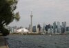 Capture of Toronto's iconic skyline featuring the CN Tower and waterfront on a calm day.