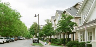 Charming Vancouver street with families enjoying a day outdoors among lined trees and houses. Urban community scene.