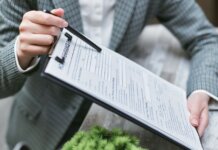 Канада подтвердила ставку взносов в страхование занятости (EI) на 2027 год Close-up of a businessperson holding a clipboard with an insurance document, emphasizing details.