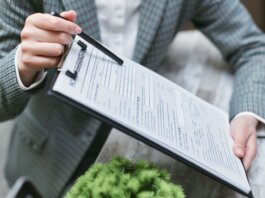 Close-up of a businessperson holding a clipboard with an insurance document, emphasizing details.