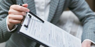 Close-up of a businessperson holding a clipboard with an insurance document, emphasizing details.