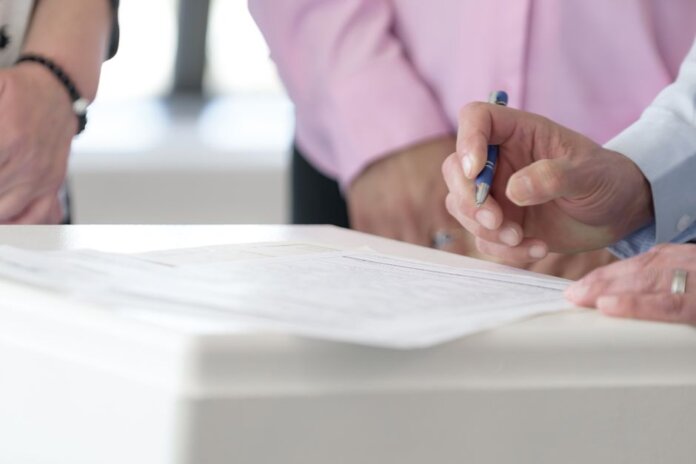 Close-up of hands signing documents in an office setting, emphasizing collaboration and decision-making. Close-up of hands signing documents in an office setting, emphasizing collaboration and decision-making.