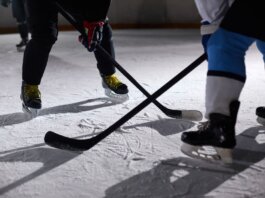 Close-up of hockey players battling for puck during an intense face-off on a lighted ice rink.