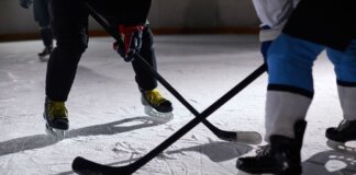 Close-up of hockey players battling for puck during an intense face-off on a lighted ice rink.