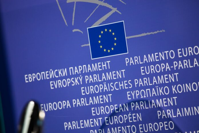 Close-up view of the European Union flag with multilingual text showing European Parliament. Close-up view of the European Union flag with multilingual text showing European Parliament.
