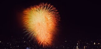 Colorful fireworks illuminate the cityscape at night, creating a festive and vibrant atmosphere.