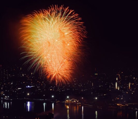 Colorful fireworks illuminate the cityscape at night, creating a festive and vibrant atmosphere.