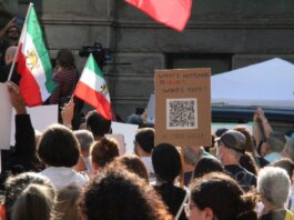 Crowd demonstrating in Vancouver with Iranian flags advocating for human rights and freedom.