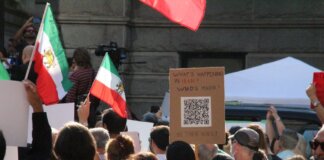 Crowd demonstrating in Vancouver with Iranian flags advocating for human rights and freedom.