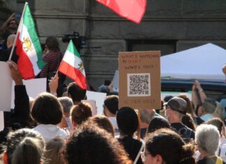 Crowd demonstrating in Vancouver with Iranian flags advocating for human rights and freedom.